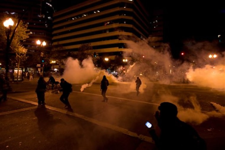 Occupy Wall Street protesters run from tear gas deployed by police at 14th Street and Broadway in Oakland, Calif., Tuesday, Oct. 25, 2011. (AP Photo/Darryl Bush)